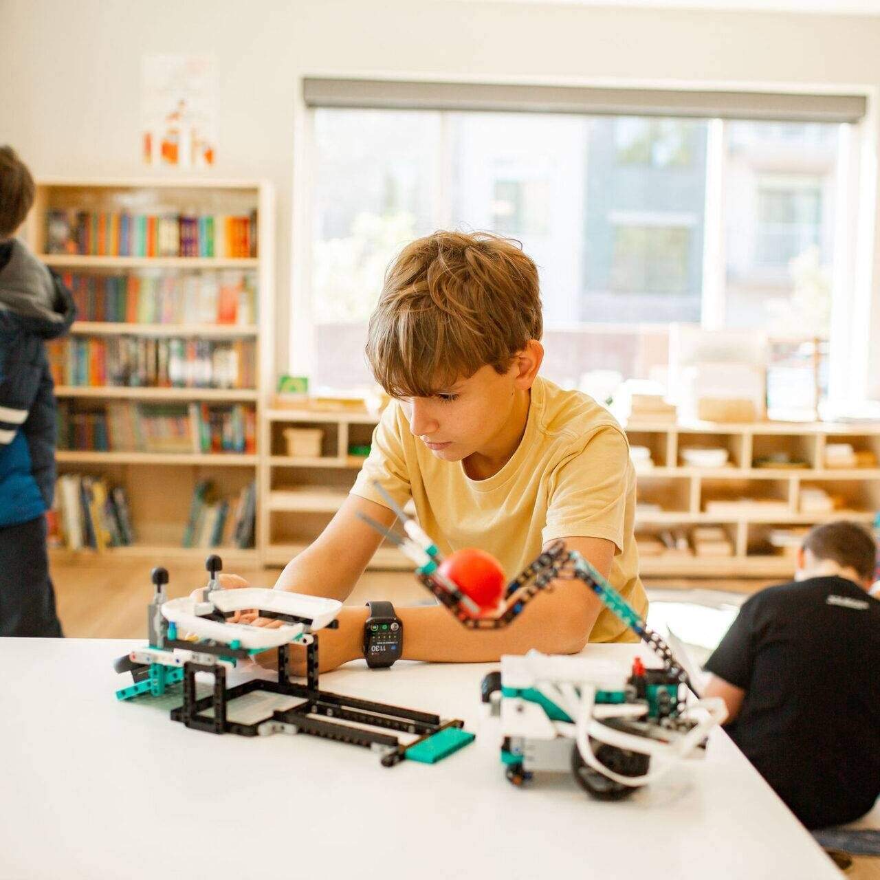 a student at Acton Academy St. George, a private school, is building and testing lego robotics on a white table